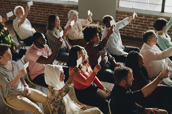 Image of people holding up pieces of paper with their vote.