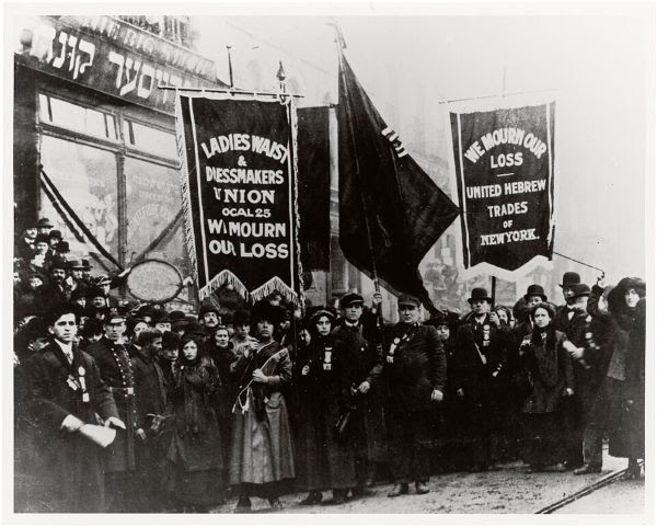 A group of men and women dressed in all black standing on a street.