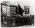 A group of men and women dressed in all black standing on a street.