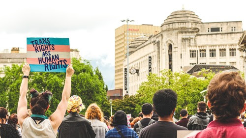A crowd of people holding a sign that says "Transgender Rights are Human Rights"